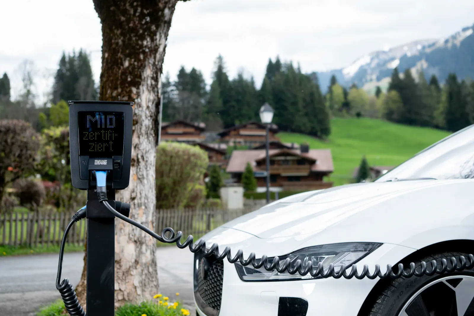 An electric car charging beside a mountain landscape